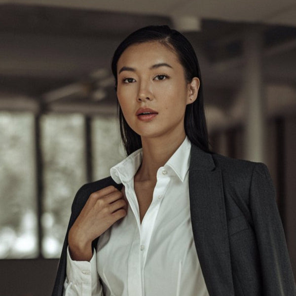 Woman in a dark blazer and white shirt standing in an indoor setting