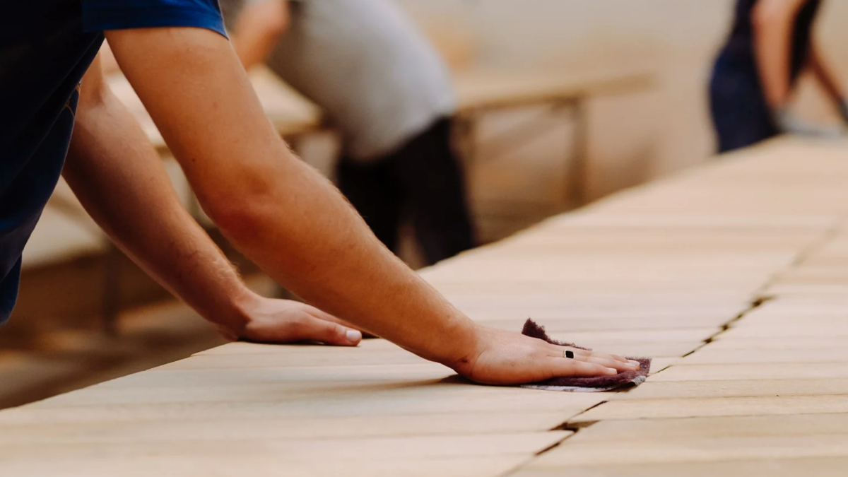 Person sanding a wooden surface with a cloth