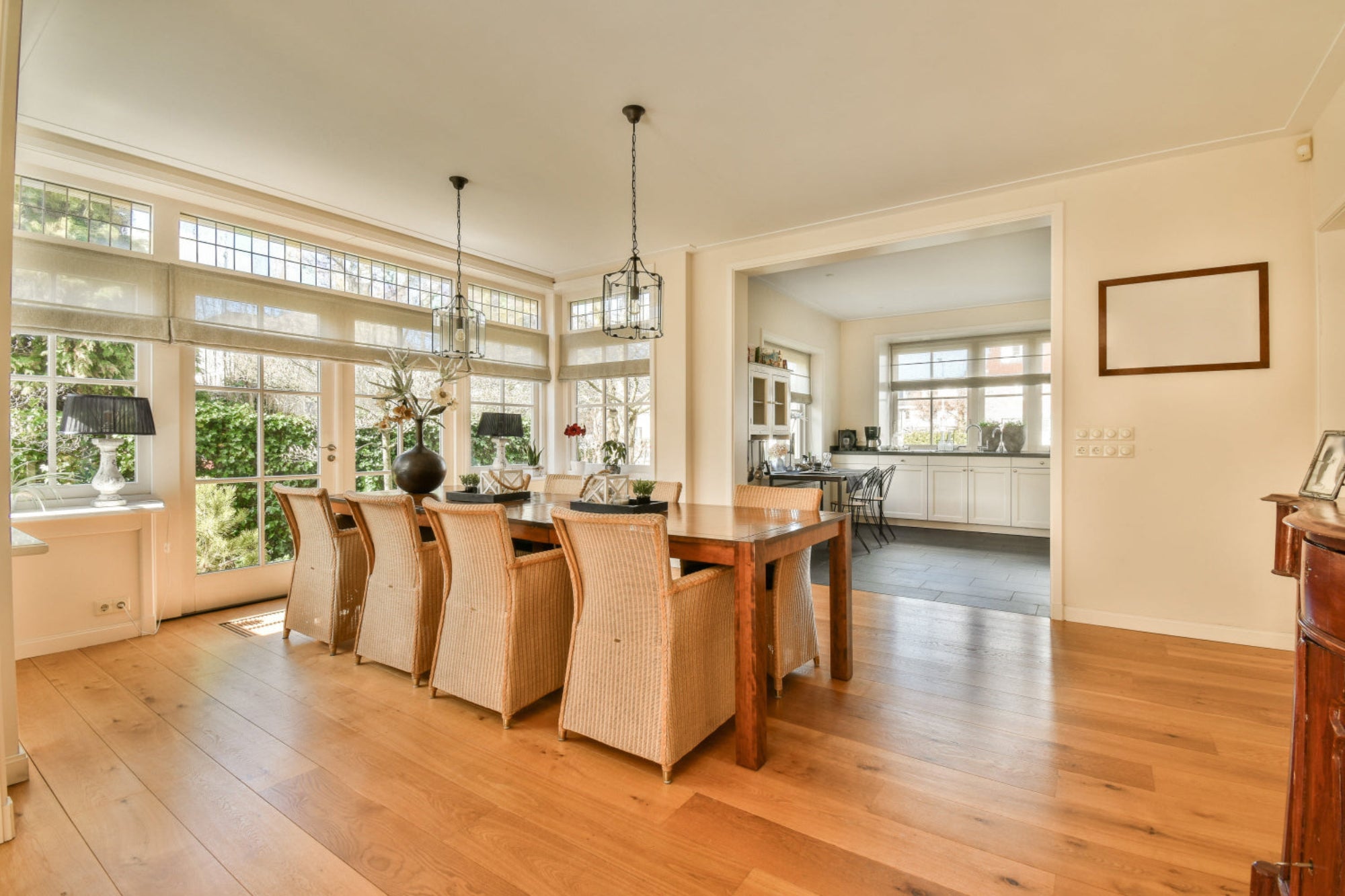 Modern kitchen with wooden dining table and chairs, large windows, and a view of the garden.
